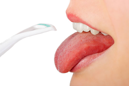 close up of a patient with their tongue stuck out about to clean with a tongue scraper